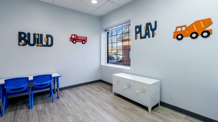 A play room with chairs and drawers, wall decorations intended for children include fun words and trucks. Office of Creekside Autism Center