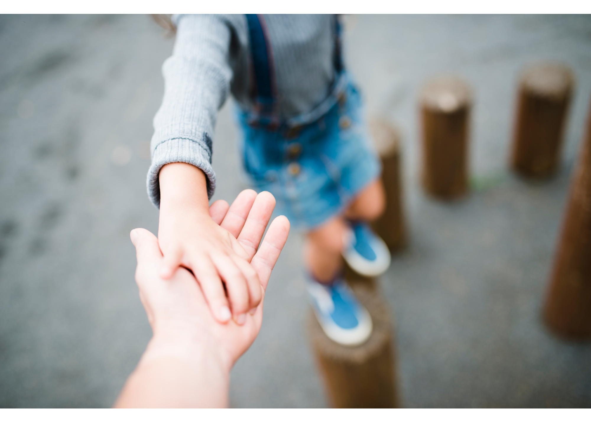 Creekside Autism Center ABA Therapy - child and adult hold hands while child plays on playground